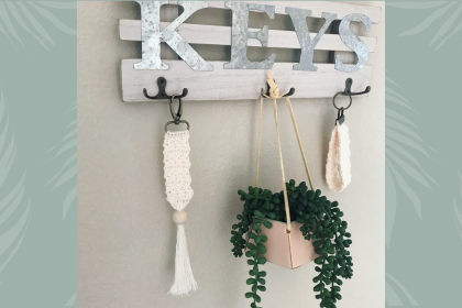 two cream keychains hanging on a key rack with small plant