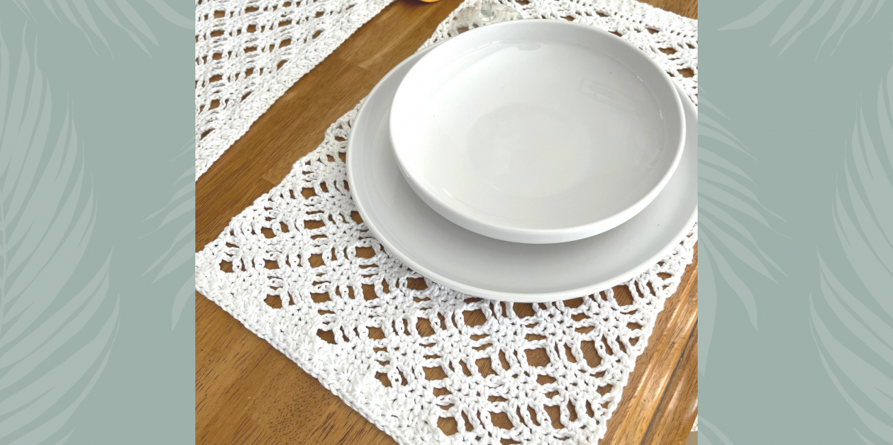 angle view of crochet placemat under dishes atop a wood table