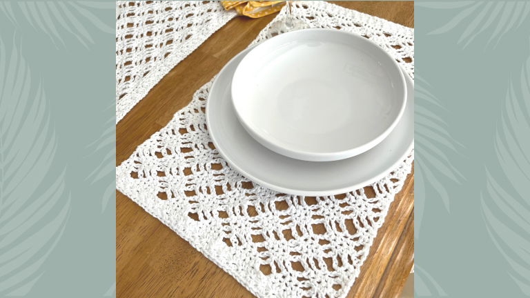 angle view of crochet placemat under dishes atop a wood table