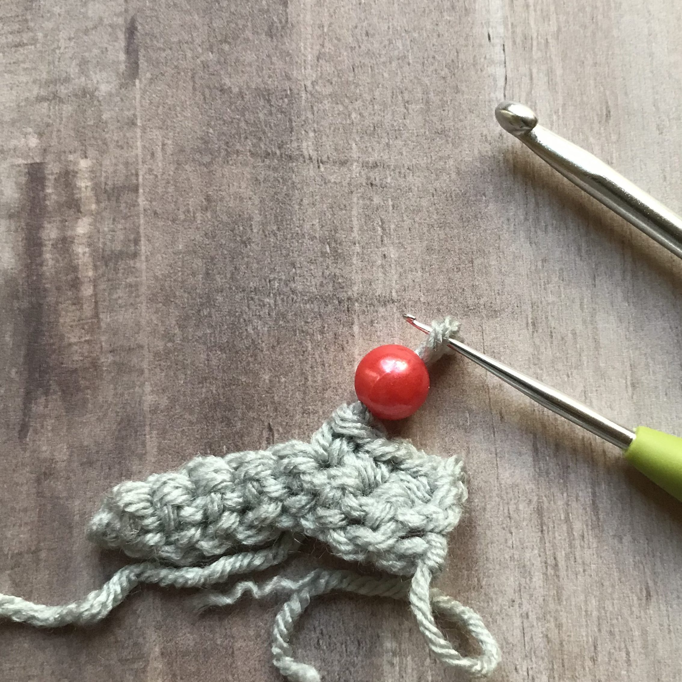 closeup of moving bead from small crochet hook to crochet fabric