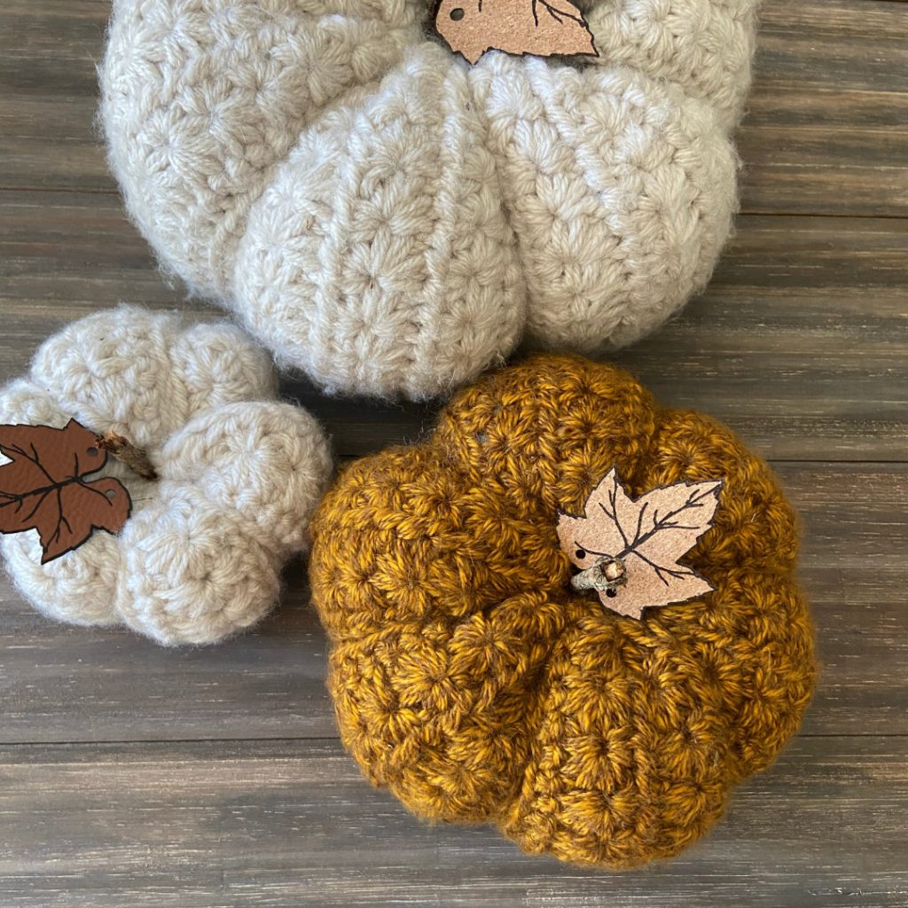 3 cream and gold crochet pumpkins on wood background
