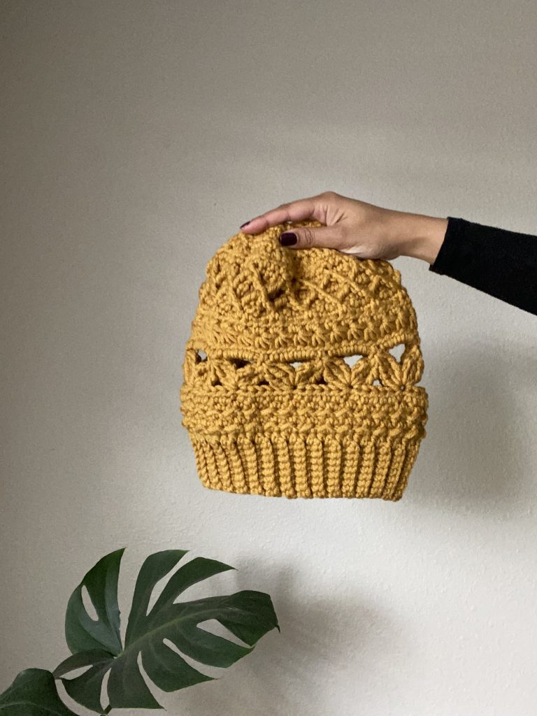 hand holding out yellow crochet beanie 