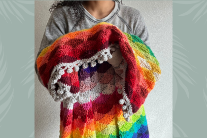 model holding colorful crochet blanket