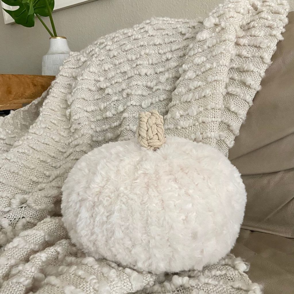 faux fur crochet pumpkin on sofa with cream textured blanket
