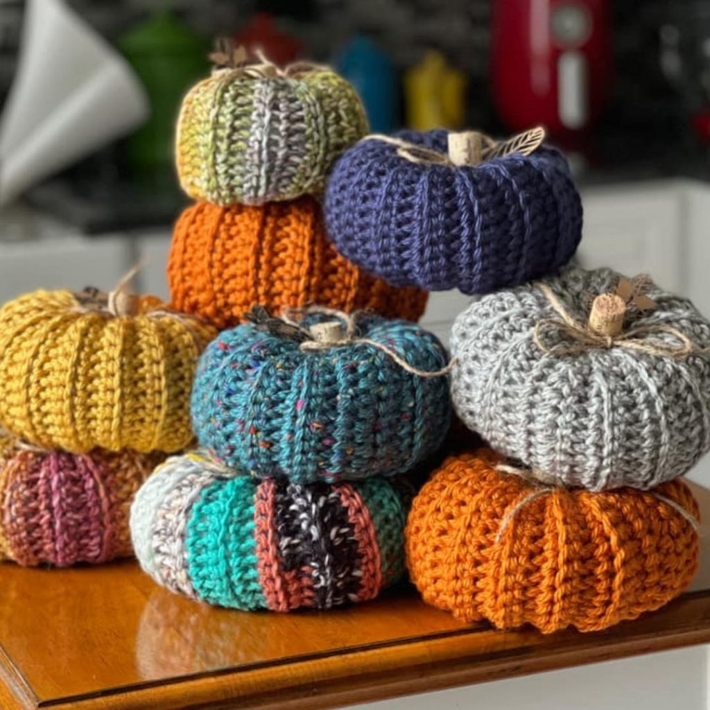 stack of brightly colored crochet pumpkins with cork stems and twine string tied around them